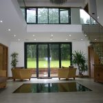 Floating staircase system and glass floor section looking into basement swimming pool area.